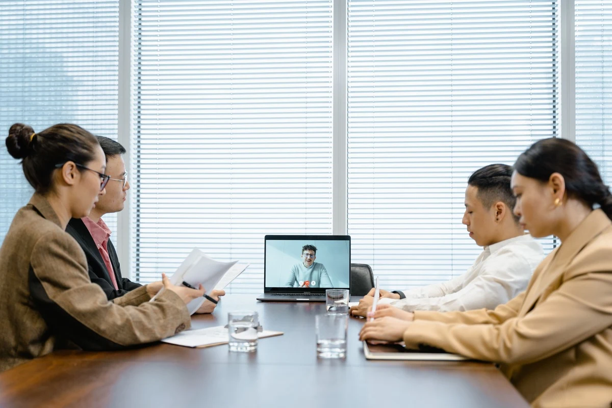 Equipa em sala de reuniões, em videochamada com um formador